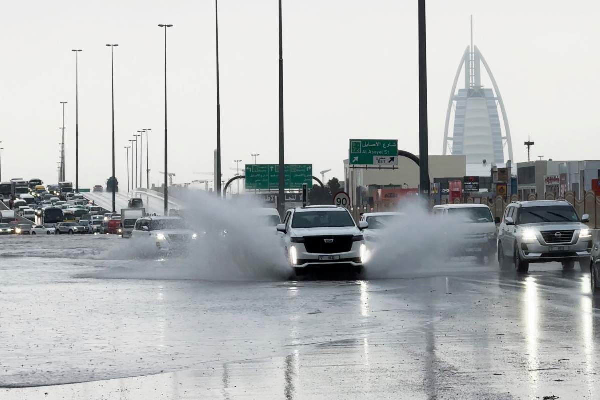 An SUV splashes through standing water on a road with the Burj Al Arab luxury hotel seen in the background in Dubai, United Arab Emirates, Tuesday, April 16, 2024. Heavy rains lashed the United Arab Emirates on Tuesday, flooding out portions of major highways and leaving vehicles abandoned on roadways across Dubai. Meanwhile, the death toll in separate heavy flooding in neighboring Oman rose to 18 with others still missing as the sultanate prepared for the storm. (AP Photo/Jon Gambrell)