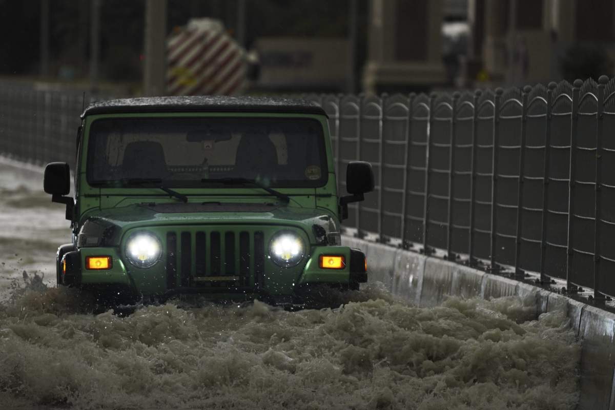 An SUV passes through standing water in Dubai, United Arab Emirates, Tuesday, April 16, 2024. Heavy rains lashed the United Arab Emirates on Tuesday, flooding out portions of major highways and leaving vehicles abandoned on roadways across Dubai. Meanwhile, the death toll in separate heavy flooding in neighboring Oman rose to 18 with others still missing as the sultanate prepared for the storm. (AP Photo/Jon Gambrell)