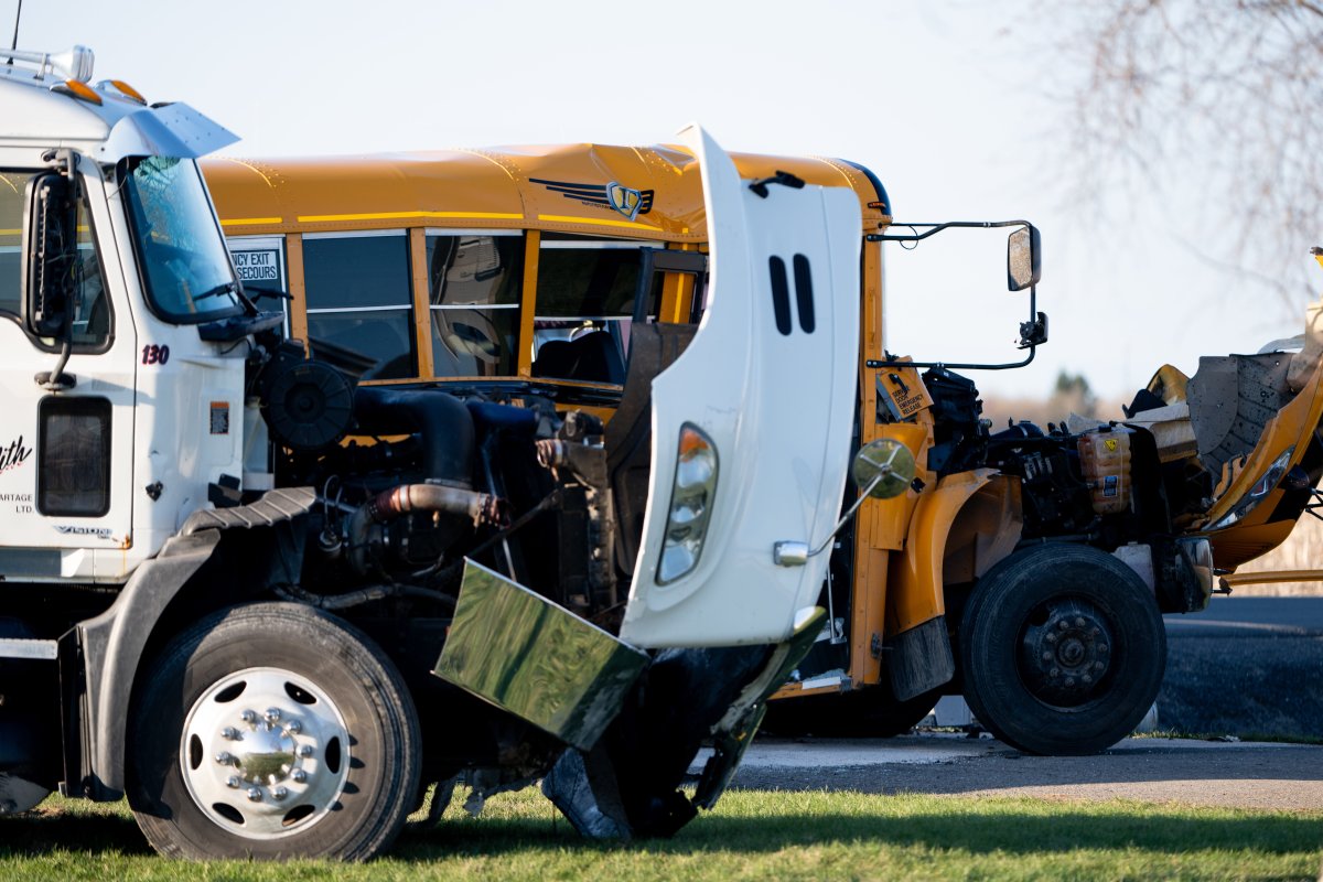 Damage is seen to a school bus and truck as officers from the Ontario Provincial Police (OPP) work the scene of a motor vehicle crash in the Township of Russell, Ont., Monday, April 22, 2024. THE CANADIAN PRESS/Spencer Colby.