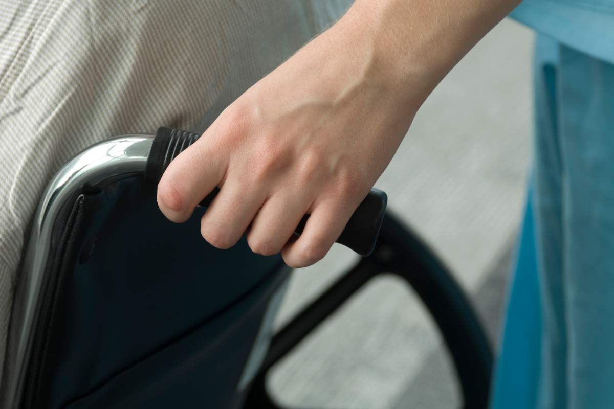 A person pushes a wheelchair in a stock photo illustration.