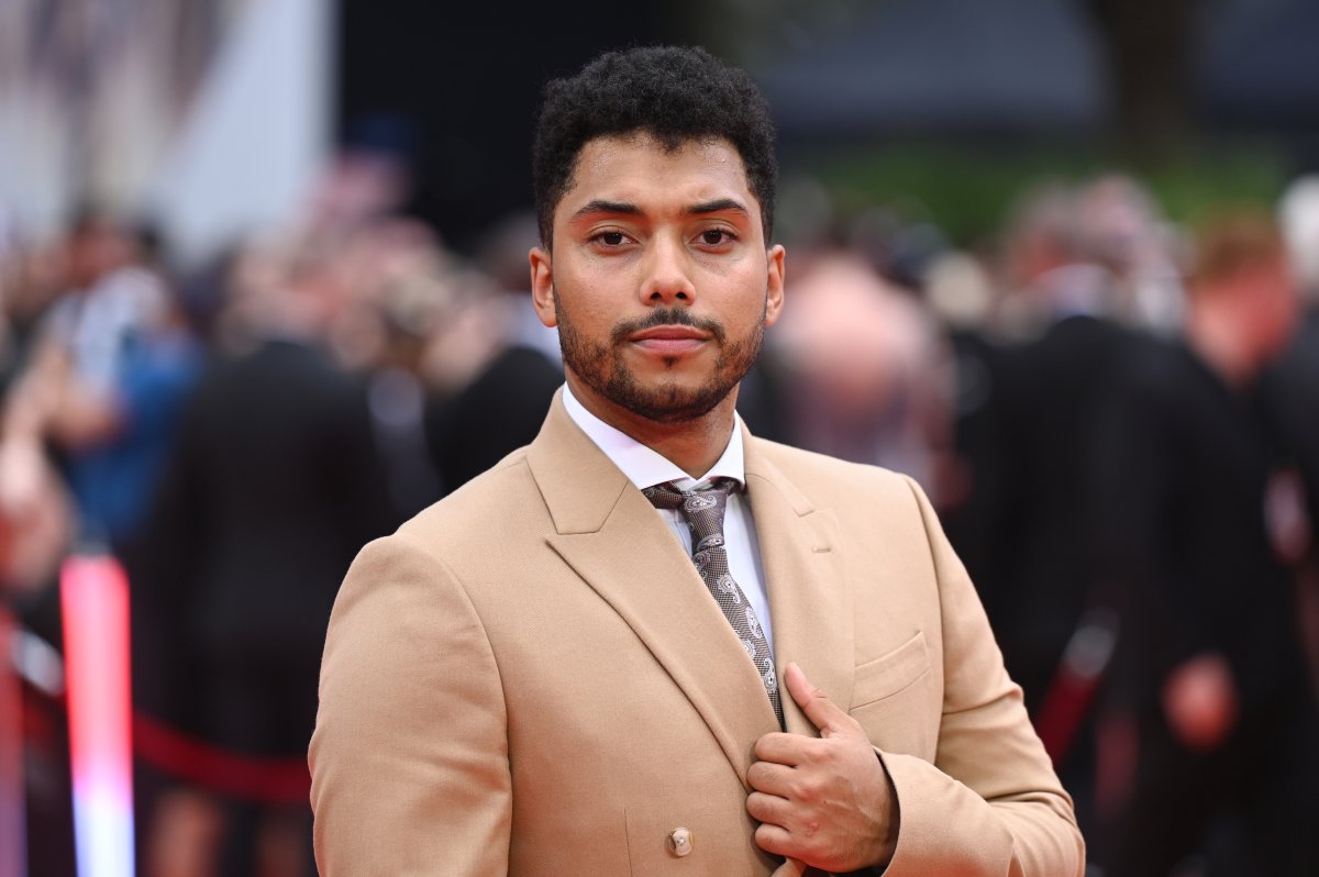 Chance Perdomo. He is wearing a brown suit jacket and a tie.