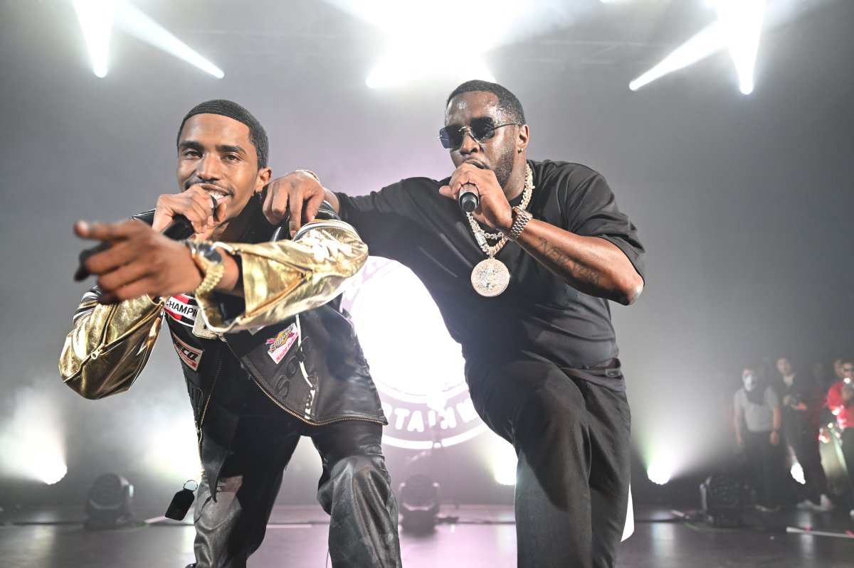Christian "King" Combs and Sean "Diddy" Combs on stage. They are both holding microphones and are leaning toward the camera.