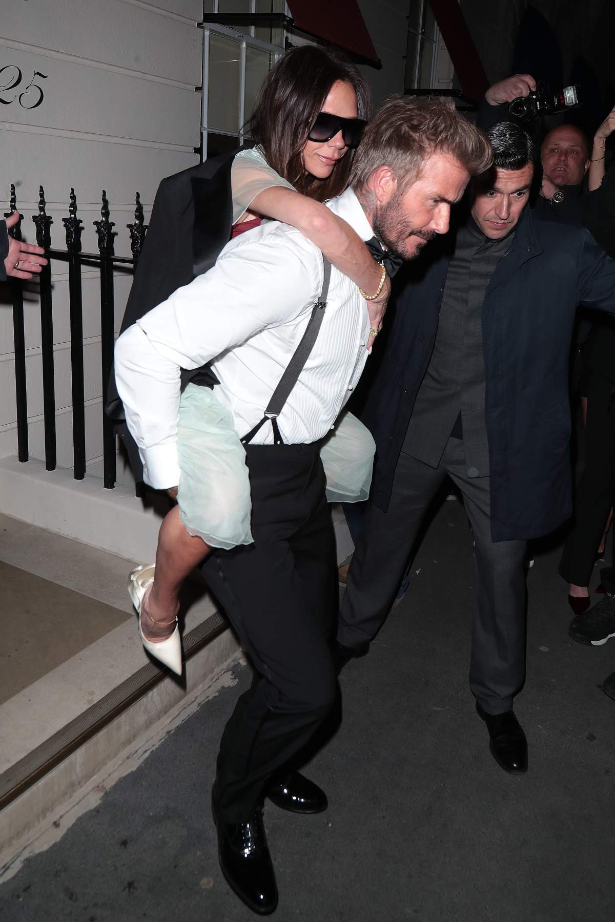 David Beckham carries Victoria Beckham on his back as the pair leave Victoria's 50th Birthday Party at Oswald’s on April 20, 2024 in London, England.