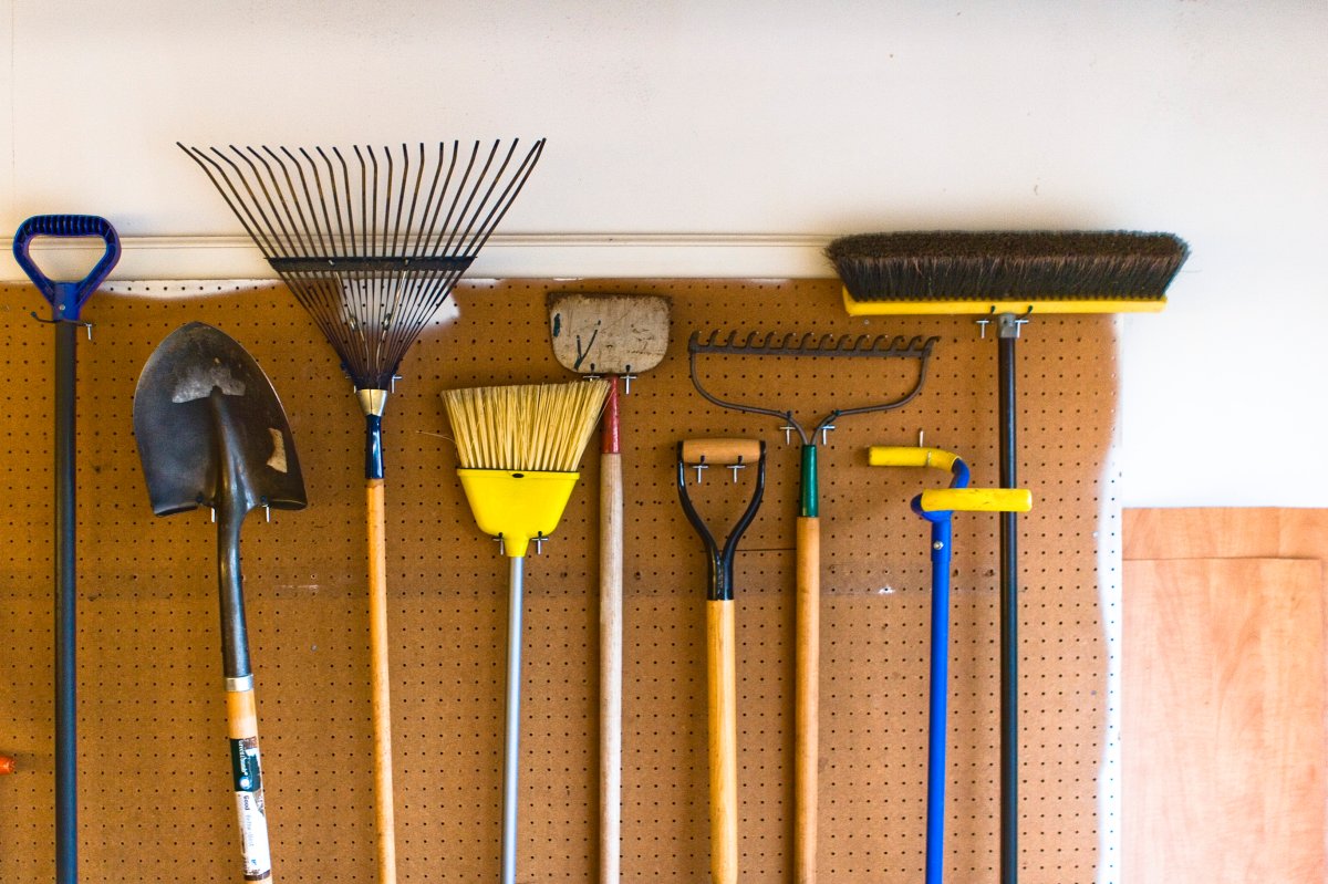 Household and garden tools stored in garage on pegboard wall in an organized and tidy fashion