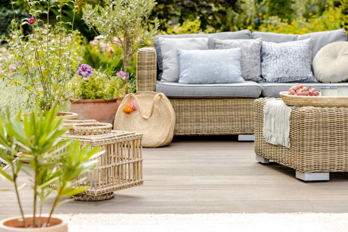 Comfortable wicker garden furniture with grey pillows in beautiful backyard