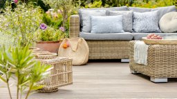 Comfortable wicker garden furniture with grey pillows in beautiful backyard