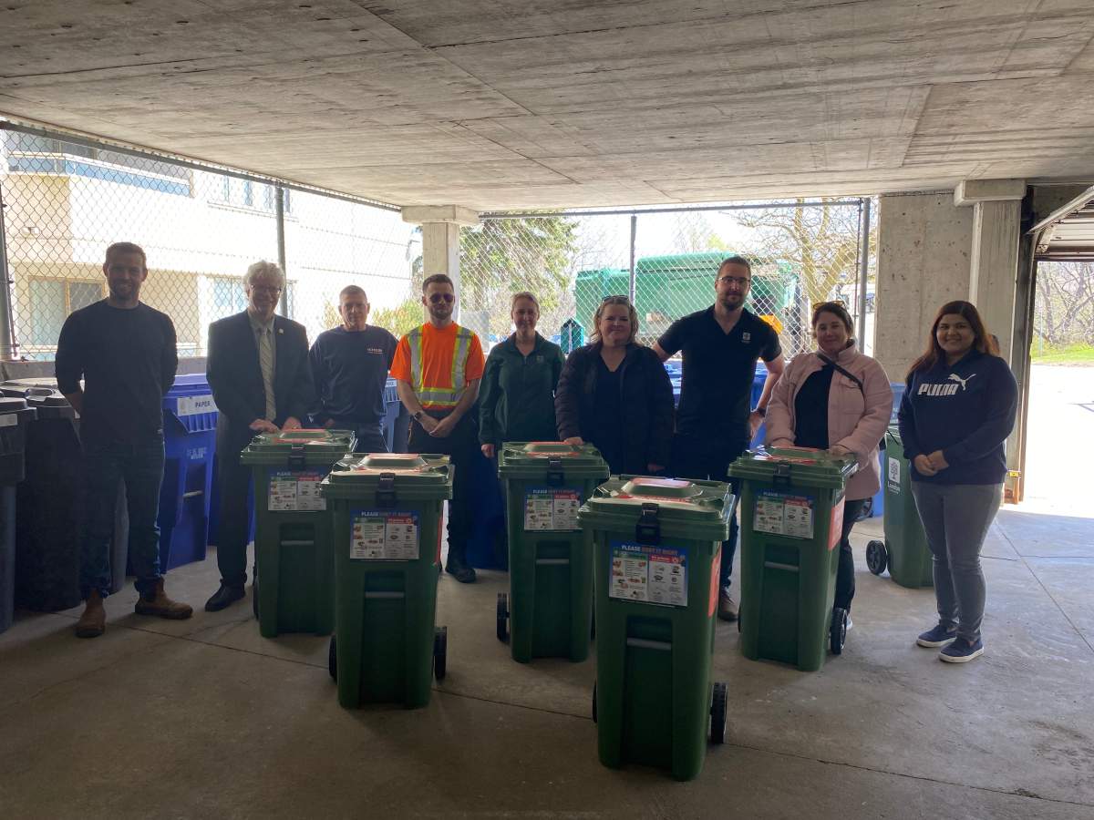 Tim Colon, Jay Stanford, Tony, Joey Machado, Elizabeth Poloza, Lisa Smith, William Robert, Jana Corby, Tanvi Jetly in front of the new multi-unit residence green bins.