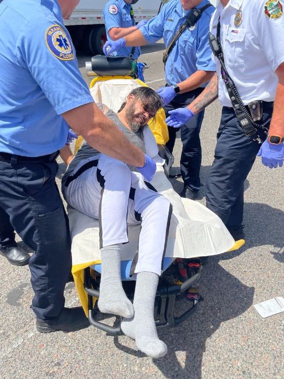 Walter Medina being detained on what appears to be a stretcher, surrounded by authorities.