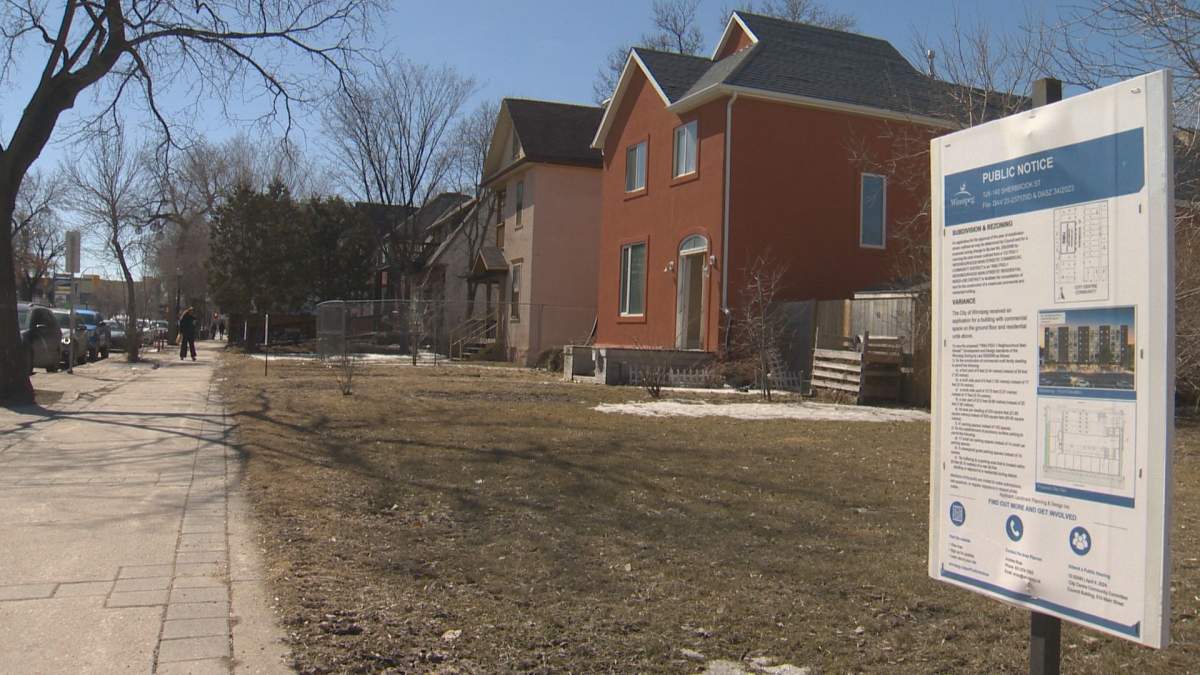 A notice of hearing sign in the foreground, old houses in the background