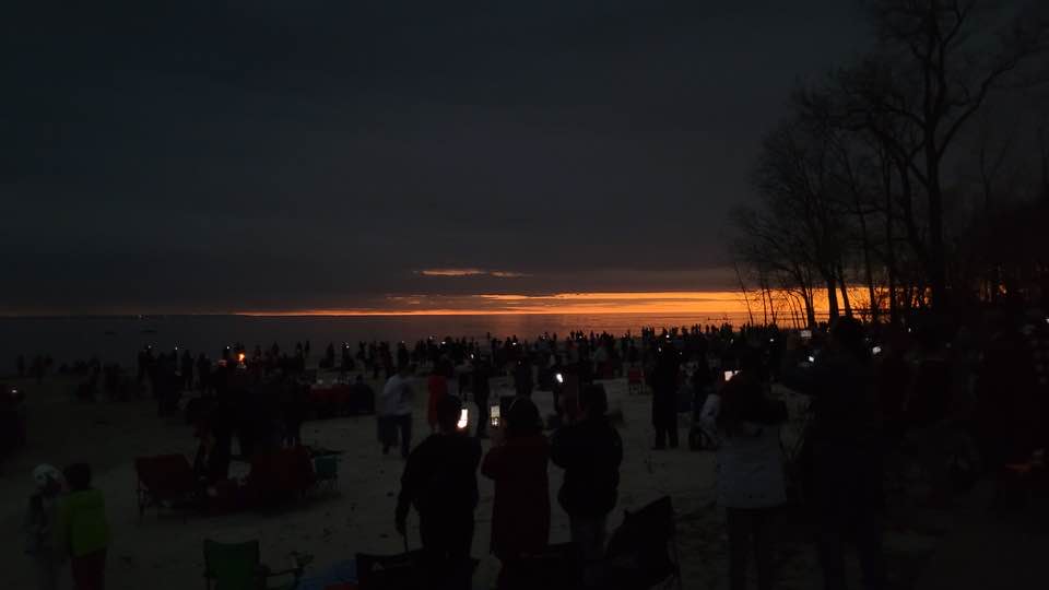 People standing on a beach in the dark.