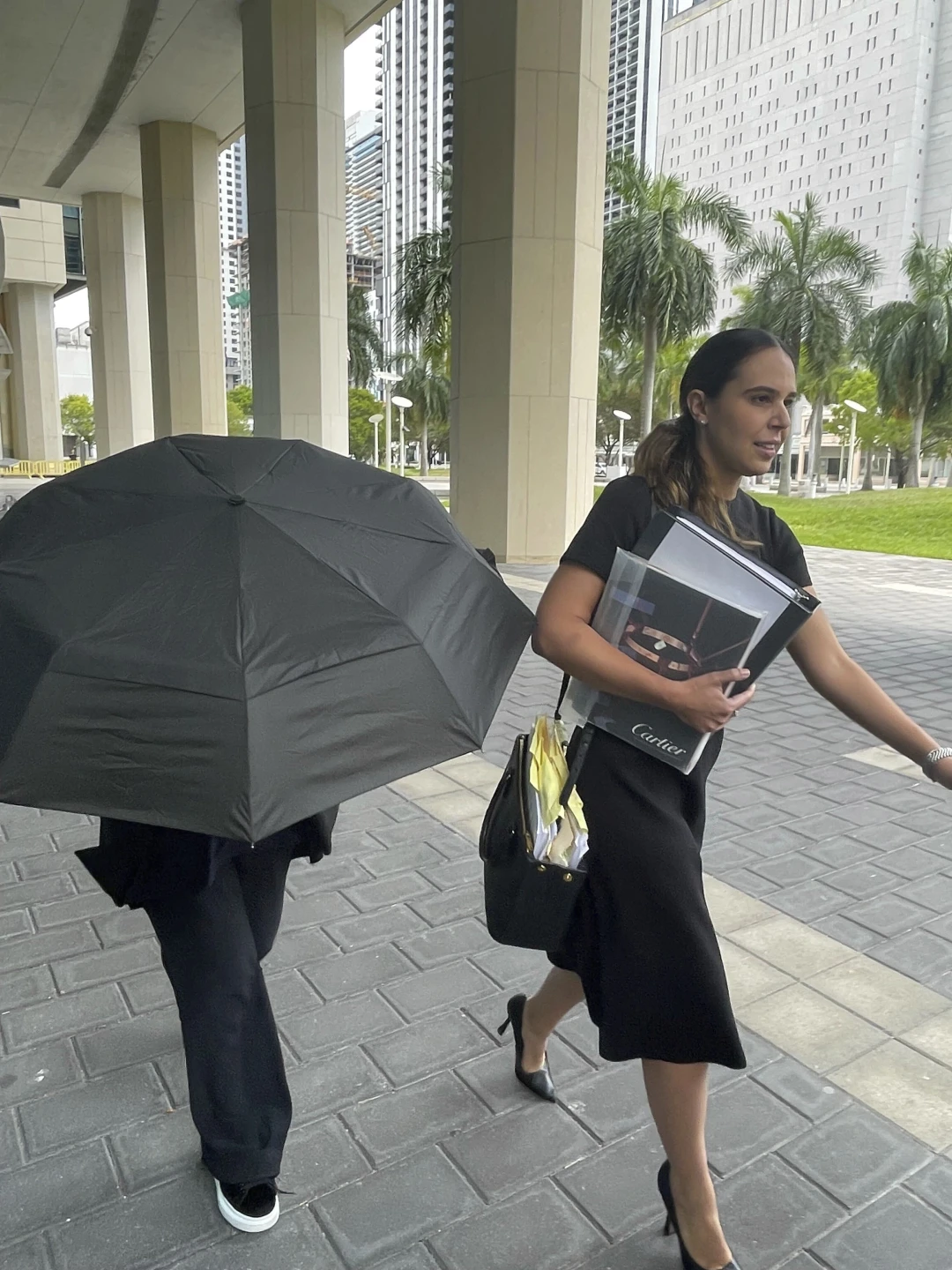 Nancy Gonzalez. hiding under an umbrella as she enters the courthouse next to her lawyer.
