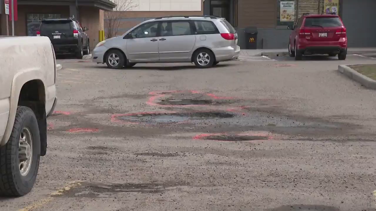 Southeast Calgary residents frustrated after strip mall parking lot potholes damage vehicles