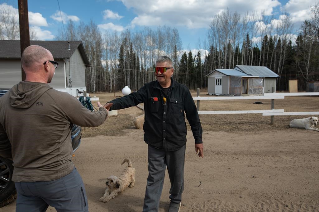 Chard Metis Nation President Raoul Montgrand, right, greets Alex Okinczyc, community and Indigenous affairs representative for Cenovus, outside Montgrand's new house in Janvier, Alta., on Tuesday April 23, 2024. Montgrand wanted other people to get the houses first but accepted the upgrade, funded in partnership with Cenovus, when he took custody of his granddaughters.