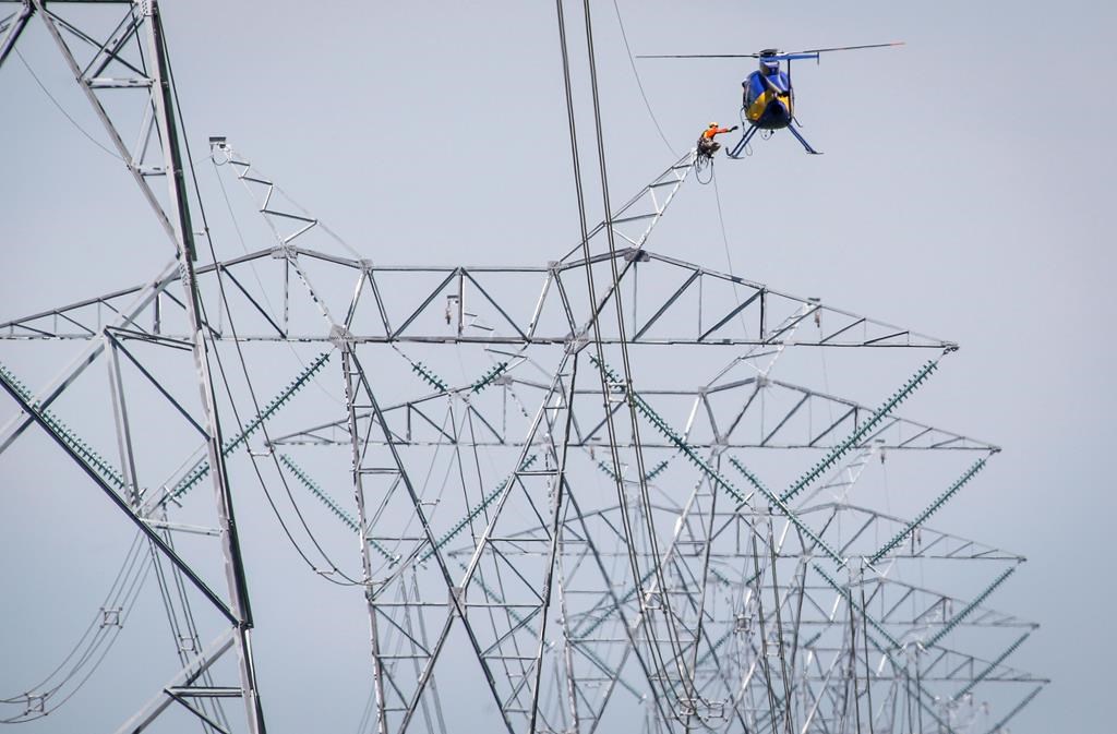 The Saskatchewan and Alberta governments have signed a memorandum of understanding to share information about nuclear power generation. A lineman reaches for a lift from a helicopter as work continues on twinning power lines that run from Calgary to Edmonton near Carstairs, Alta., Wednesday, July 23, 2014.THE CANADIAN PRESS/Jeff McIntosh.