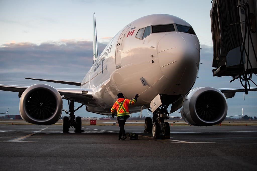 A ground worker approaches a WestJet Airlines Boeing 737 Max aircraft after it arrived at Vancouver International Airport in Richmond, B.C., on Thursday, January 21, 2021.