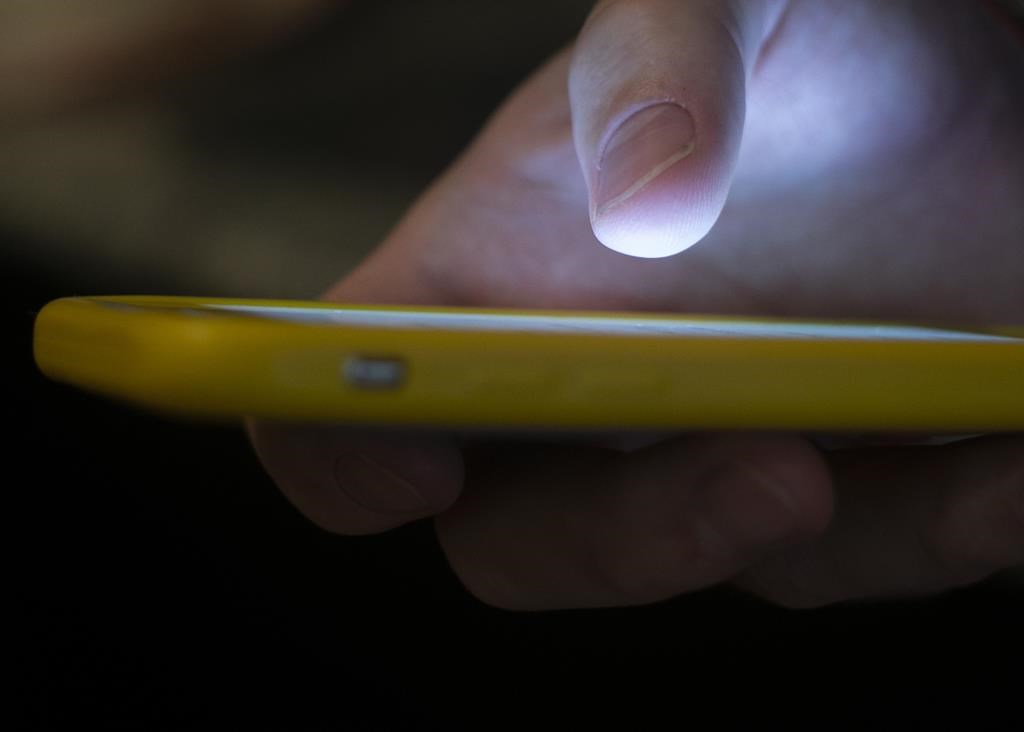FILE - In this Aug. 11, 2019, file photo, a man uses a cell phone in New Orleans. (AP Photo/Jenny Kane, File).