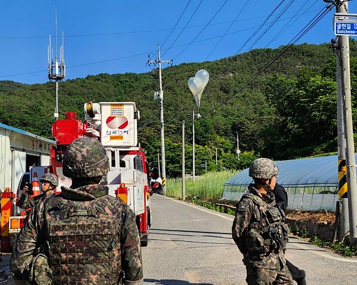 In this photo provided by Jeonbuk Fire Headquarters, balloons with trash hang on electric wires as South Korean army soldiers stand guard in Muju, South Korea, Wednesday, May 29, 2024.