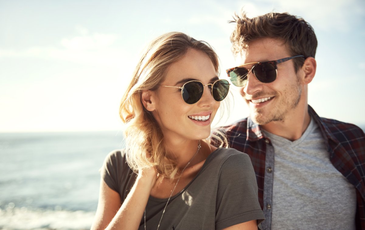 Couple on a stroll by the beach both wearing sunglasses