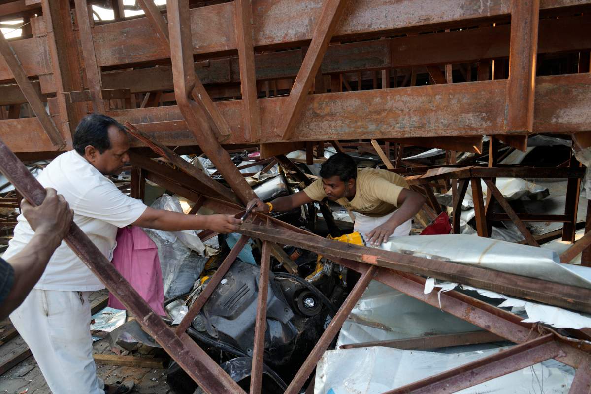 People salvage valuables from under a large billboard that collapsed Monday evening following heavy rain and thundershowers at Ghatkopar, a suburb of Mumbai, India