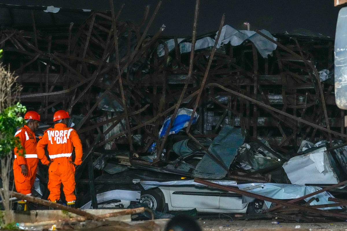 Rescuers look for victims under a billboard that collapsed following heavy rain and thundershowers in Mumbai, India