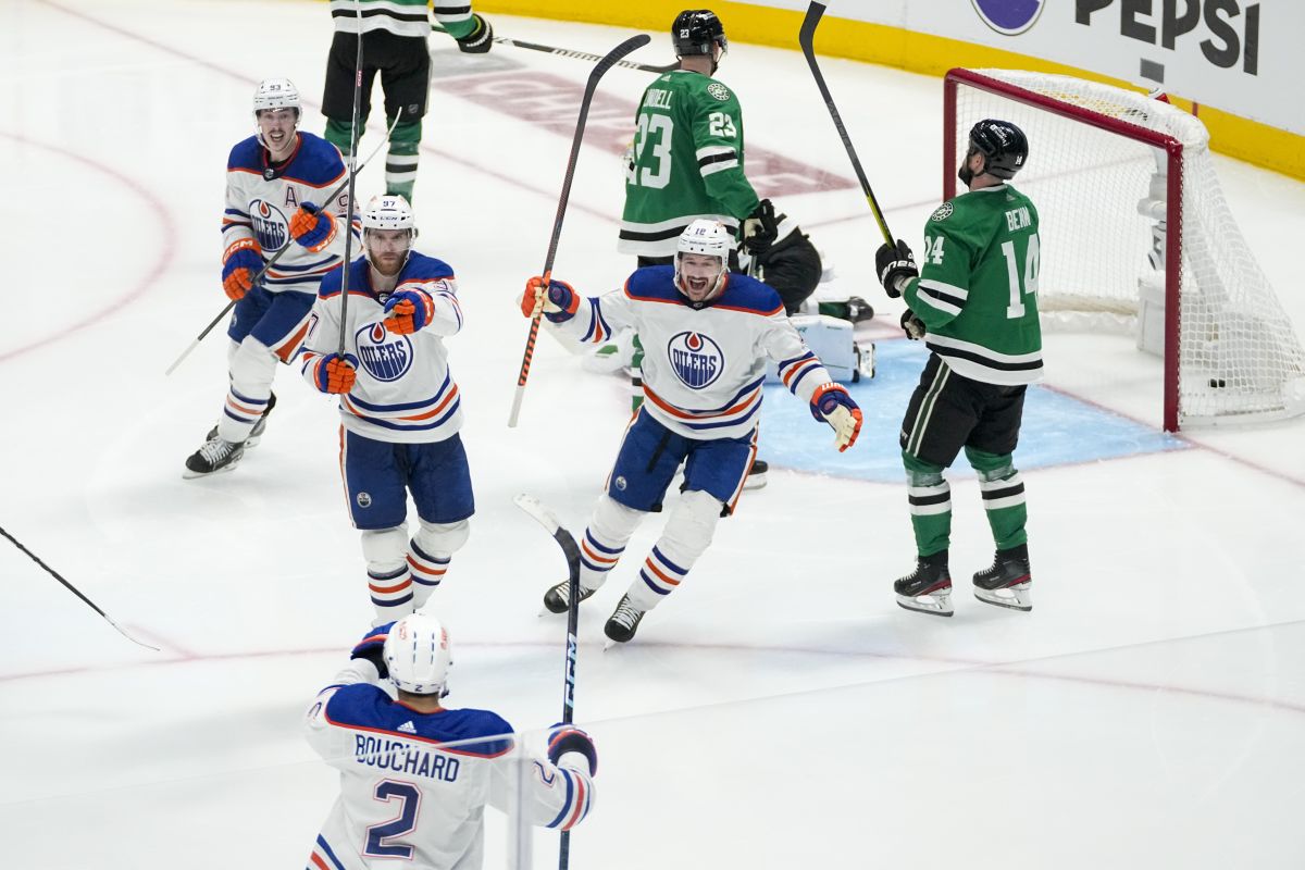 Edmonton Oilers centre Connor McDavid, centre left, gestures toward teammate defenceman Evan Bouchard (2) as teammates left wing Zach Hyman, centre right, and centre Ryan Nugent-Hopkins, top left, look on after McDavid scored the game-winning goal on an assist by Bouchard during the second overtime in Game 1 of the NHL hockey Western Conference Stanley Cup playoff finals against the Dallas Stars, Thursday, May 23, 2024, in Dallas.