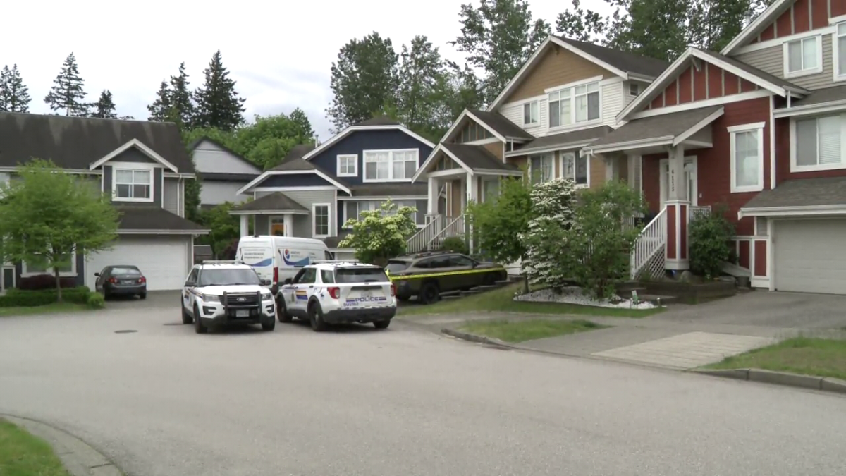 Police vehicles outside a Surrey home where two men were found dead on Wednesday.