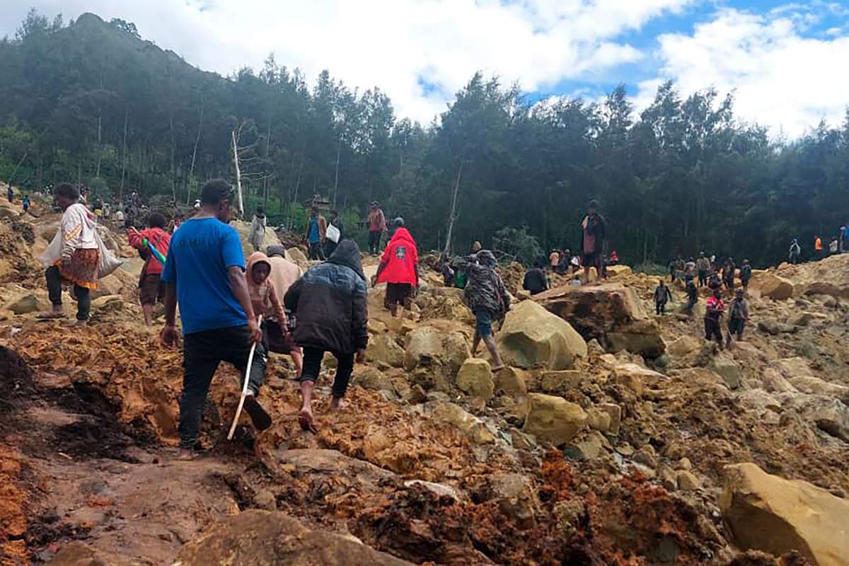 People cross over the landslide area to get to the other side in Yambali village, Papua New Guinea, Friday, May 24, 2024.