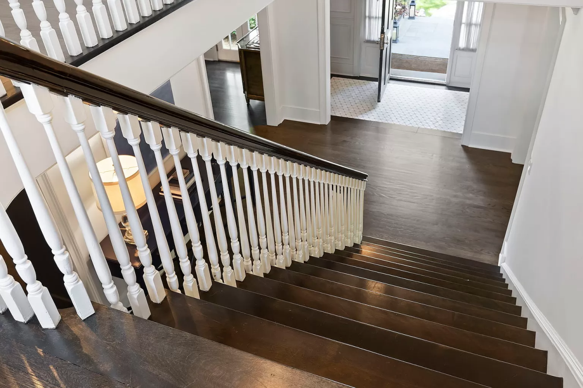 A wooden staircase, leading to a front entrance where the door is open.