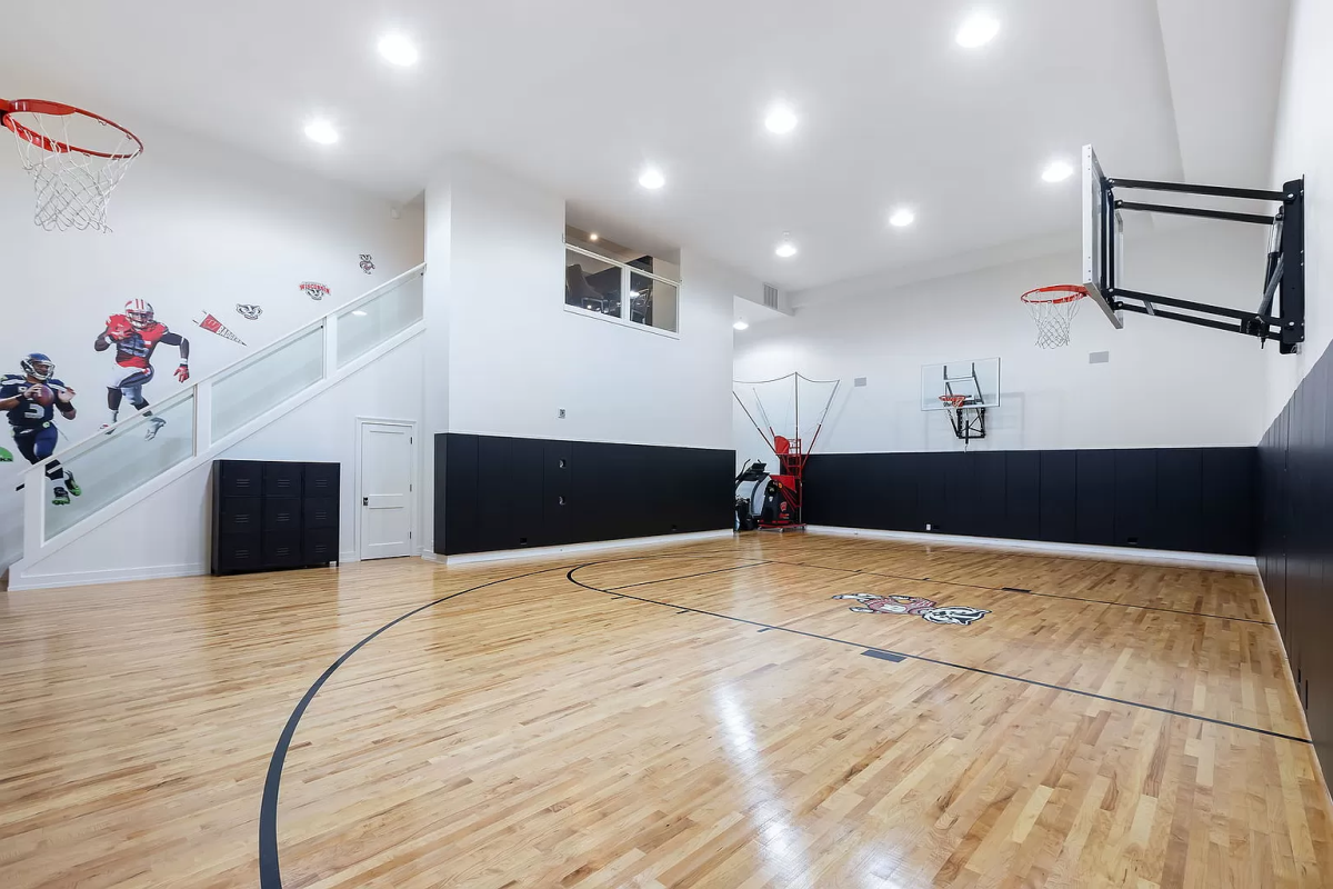An indoor basketball court. There are stairs leading to an upstairs area out of frame.