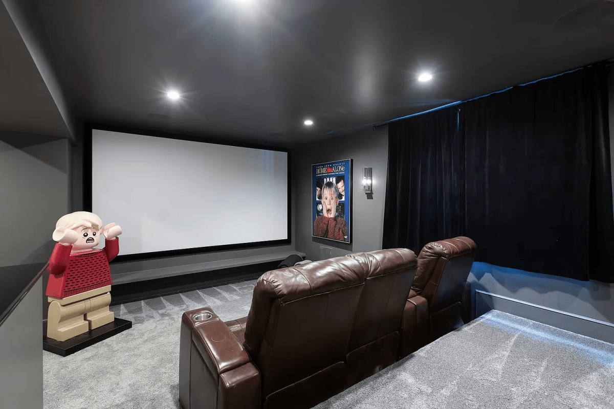 A home movie theatre. There is a 'Home Alone' poster on the wall and a big Lego figure of Kevin McAllister.
