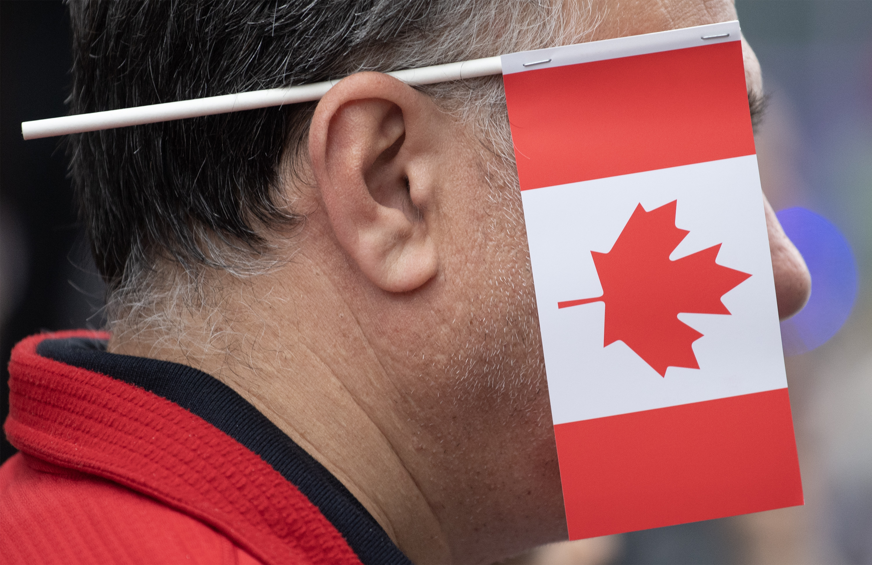 A Canadian flag covers the side of a man's face.