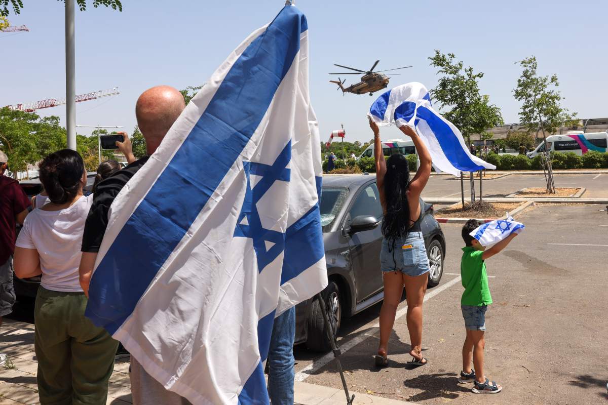 People wave Israeli flags to helicopter carrying hostages who were kidnapped in a Hamas-led attack on Oct. 7, 2023, and were just rescued as its lands at the Sheba Medical Center in Ramat Gan, Israel, Saturday, June 8, 2024.