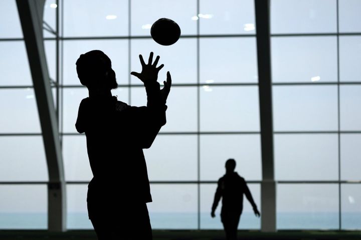Players toss the ball around in silhouette a football workout on Tuesday, March 9, 2021, in Evanston, Ill.