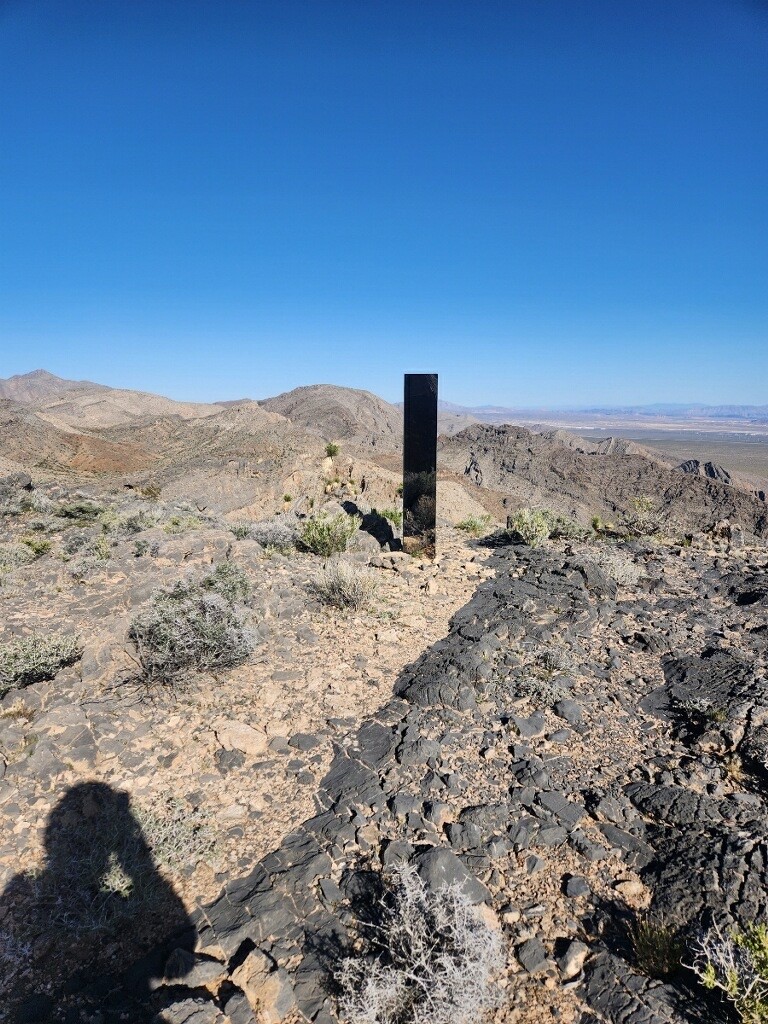 A shiny monolith on the desert ground. The photographer is casting a shadow.