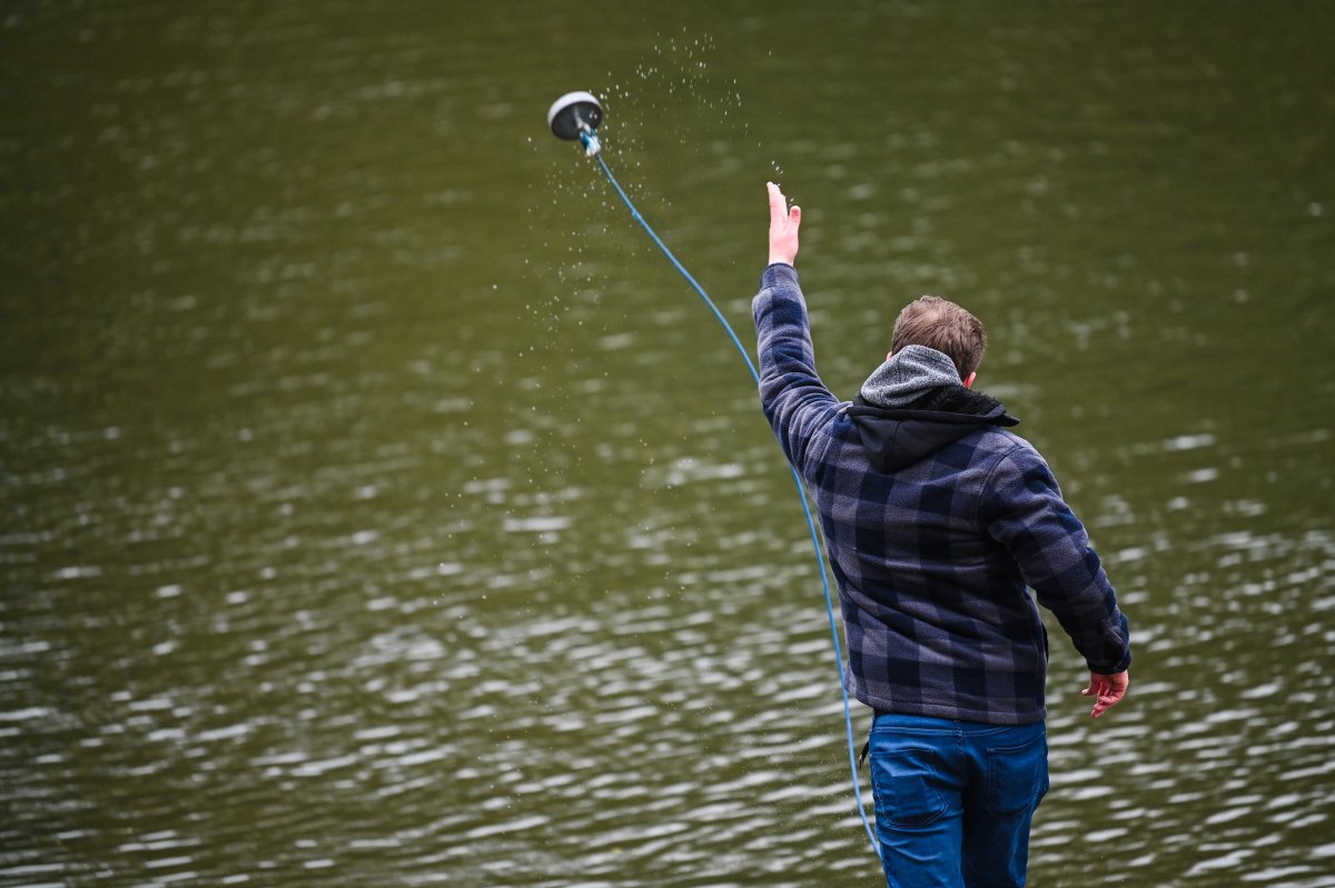 A man tosses a magnet on a fishing line into the water.