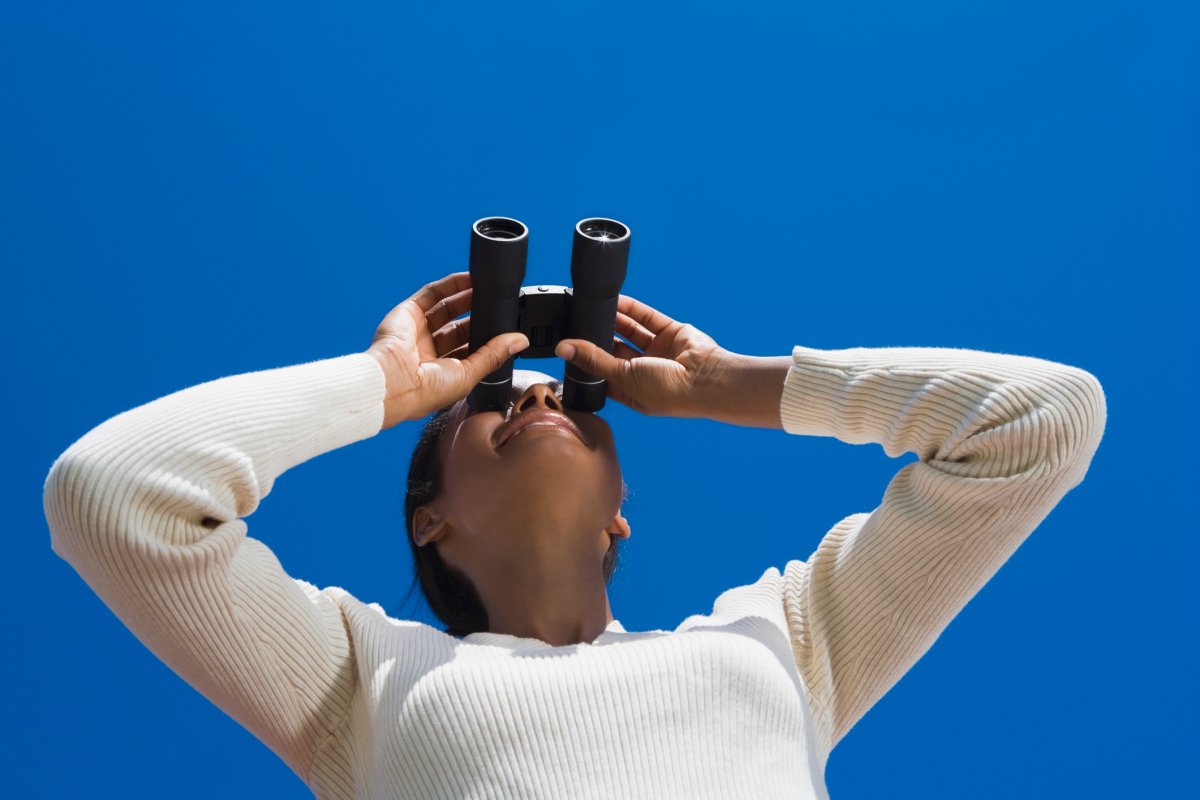 A woman looks through binoculars.