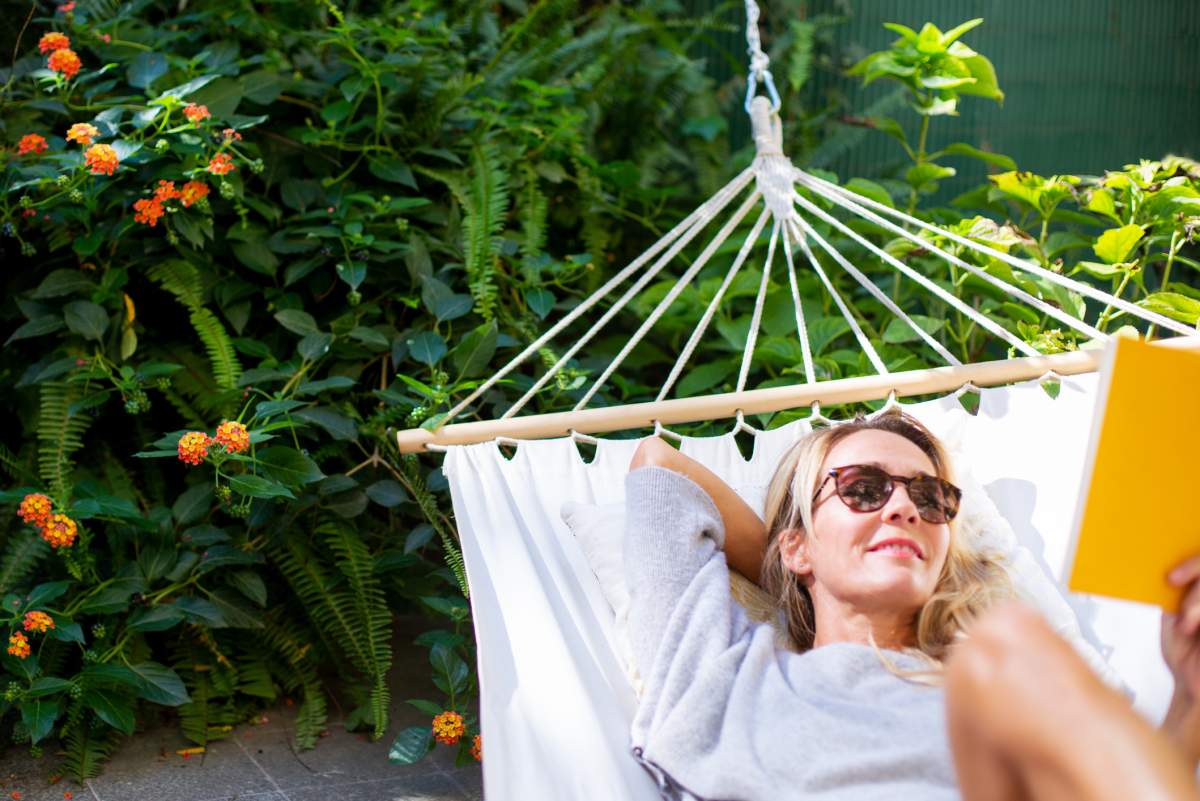 Woman relaxing in hammock, reading a book