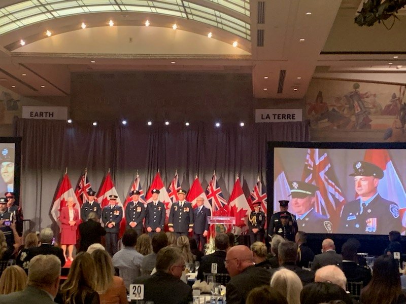 A group of firefighters in front of flags at an award ceremony.