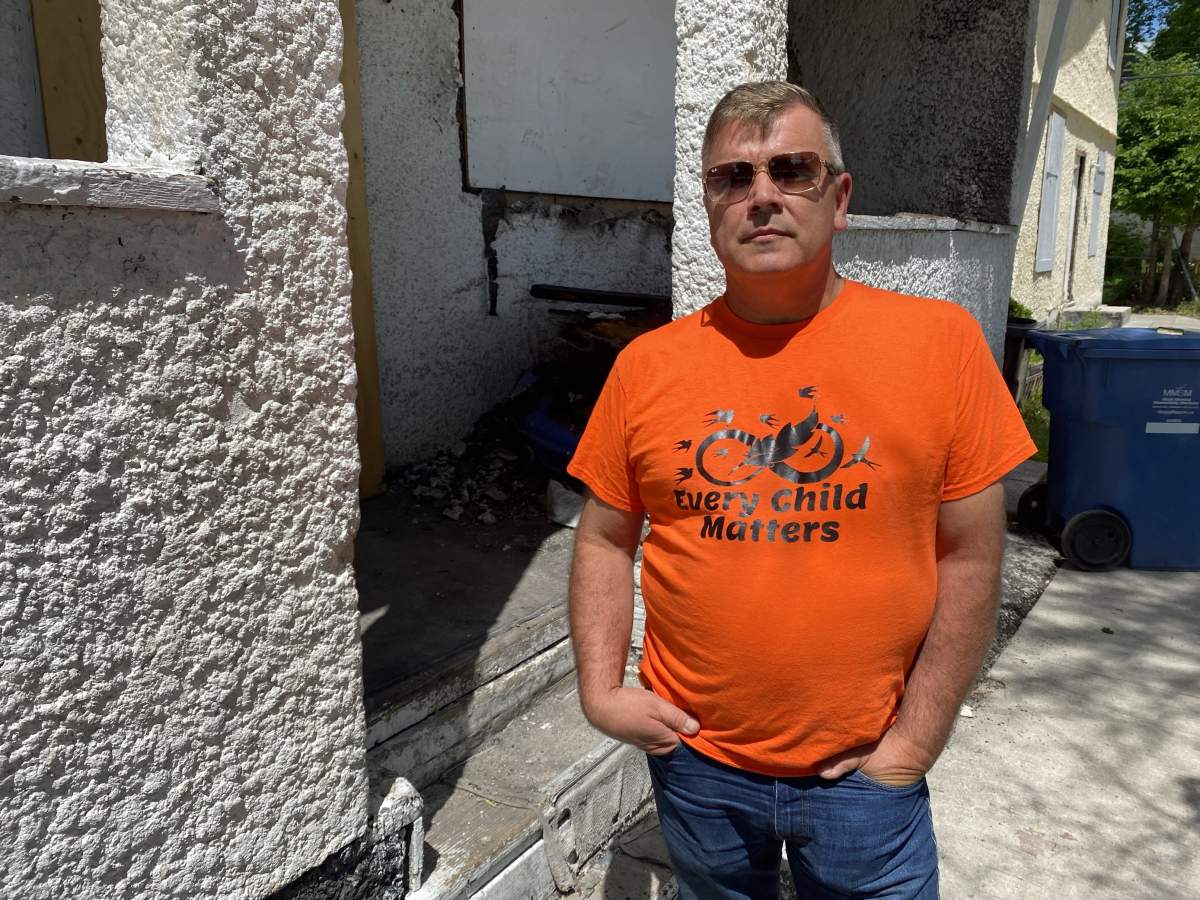 Kent Dueck stands outside of a vacant, burned home on Powers Street in Winnipeg.