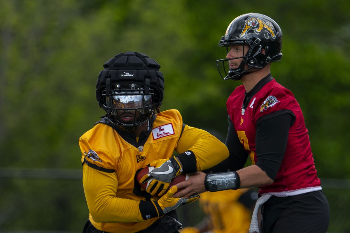 Hamilton Tiger Cats quarterback Taylor Powell (7) hands off to running back James Butler (9) during the first day of training camp at Ron Joyce Stadium at McMaster University, in Hamilton, Ont., Sunday, May 12, 2024.