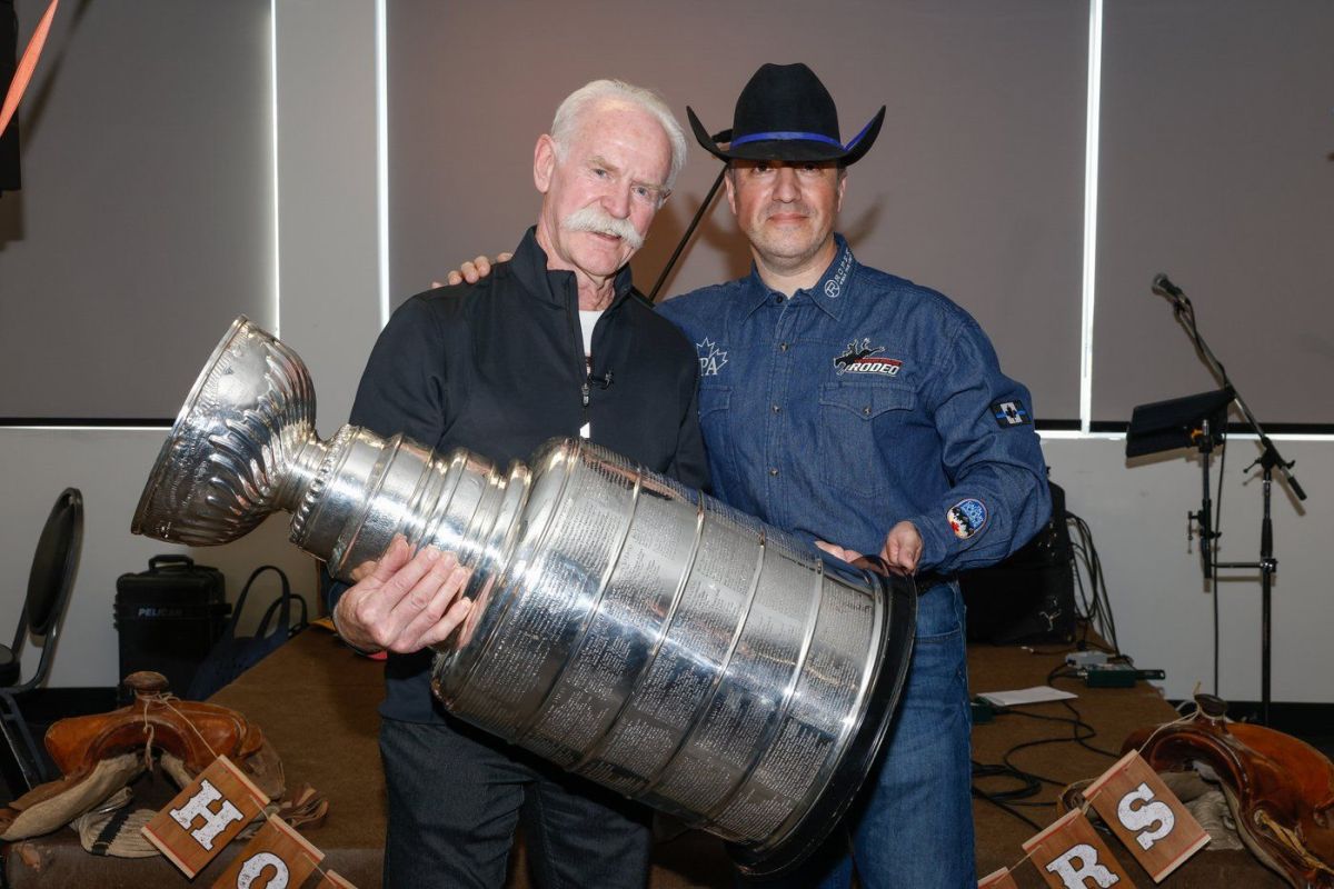 Former Calgary Flames co-captain and Hockey Hall of Famer Lanny McDonald, left, and Const. Jose Cives pose for pictures while holding the Stanley Cup in this handout image.