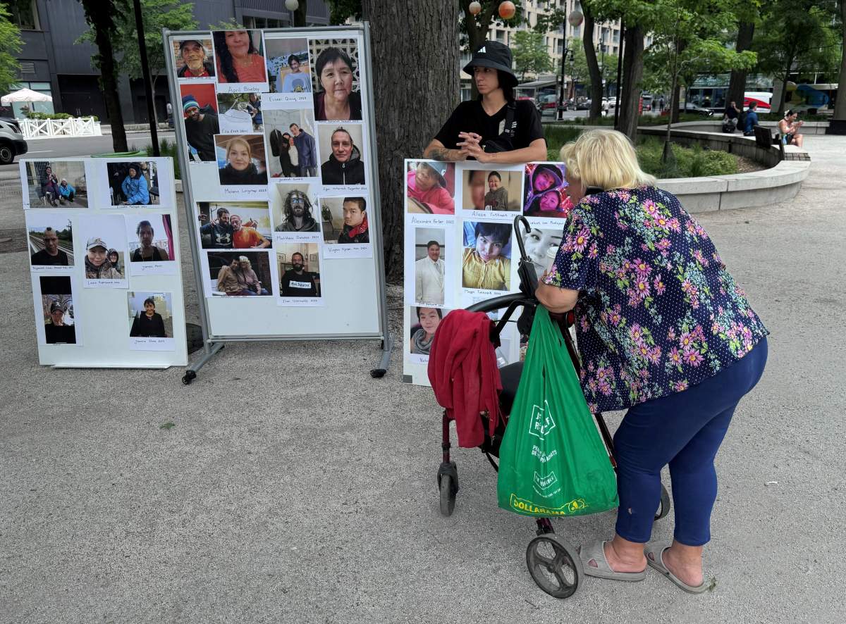 A woman looks at photos of deceased unhoused people during a memorial in their honour, in Montreal, Wednesday June 5, 2024. Advocates say the number of unhoused Montrealers who have died recently is a sign of failure, not just by governments but by the broader community. (Global News)