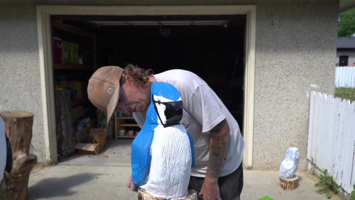 Adam Baker working on a blue jay he carved with a chainsaw.