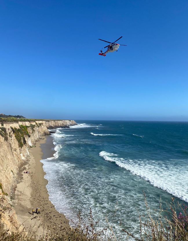 The long and narrow beach is separated from the road above by a steep and soaring cliff.