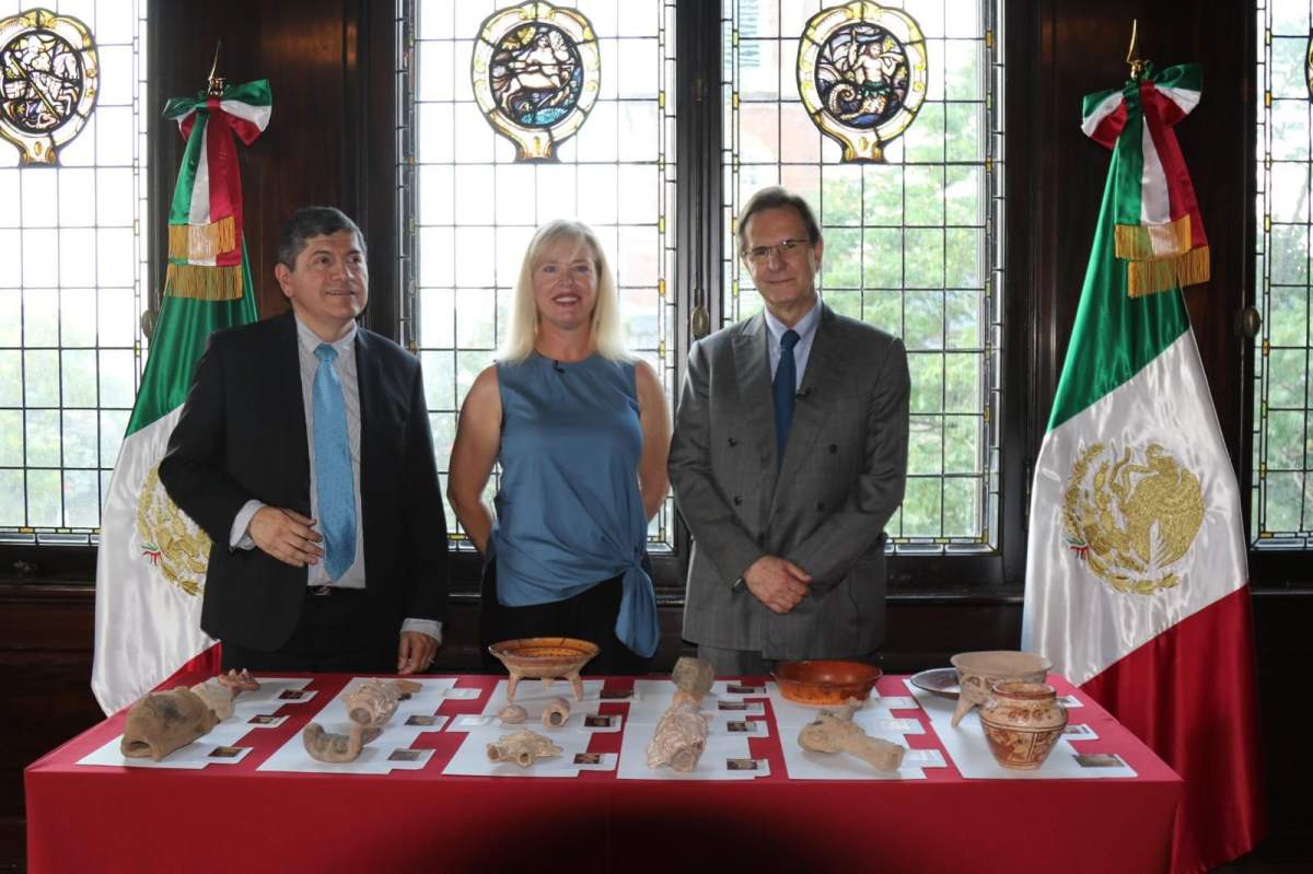 Anna Lee Dozier standing in front of a table of artefacts beside Armando Arriazola and Esteban Moctezuma Barragán.