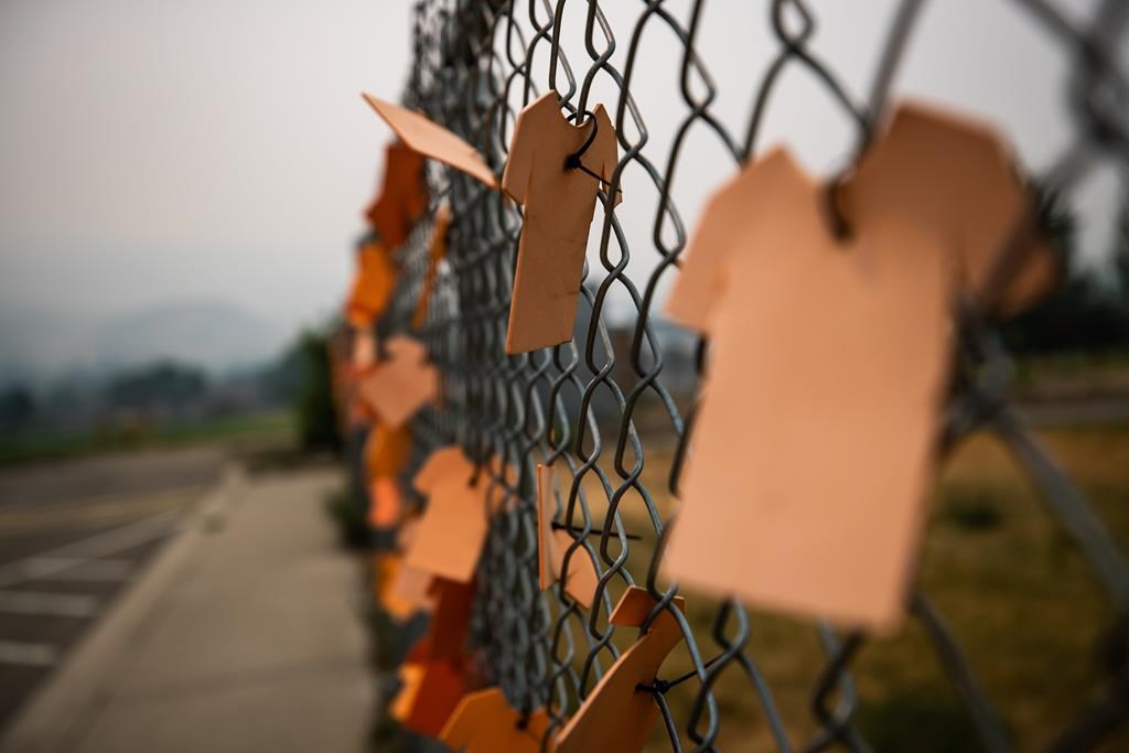 A First Nation community in northern Manitoba says ground-penetrating radar has found 150 anomalies at and around the site of a former residential school, along with 59 unmarked graves at a nearby cemetery. Cutouts of orange T-shirts are hung on a fence outside the former Kamloops Indian Residential School, in Kamloops, B.C., on Thursday, July 15, 2021. 