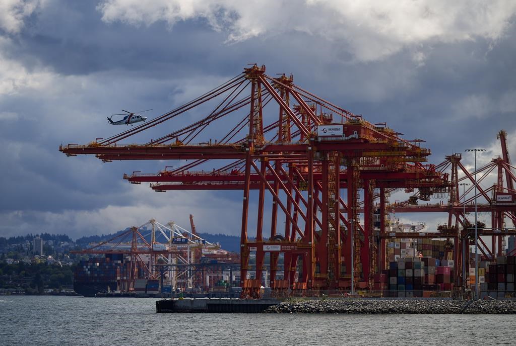 A BC Ambulance Service helicopter operated by Helijet passes gantry cranes used to load and unload cargo ships at port while preparing to land, in Vancouver, on Thursday, July 25, 2024. The BC Maritime Employers Association says it has been told by a lawyer for the port foremen's union that an industry-wide strike vote will take place in coming weeks. THE CANADIAN PRESS/Darryl Dyck.