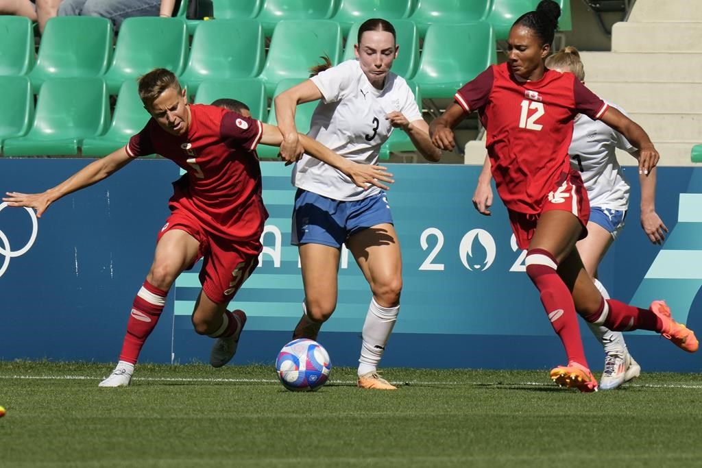 New Zealand's Mackenzie Barry, centre, competes for the ball against Canada's Quinn, left, and Jade Rose during the women's Group A soccer match between Canada and New Zealand at Geoffroy-Guichard stadium during the 2024 Summer Olympics, Thursday, July 25, 2024, in Saint-Etienne, France. Canada's women's soccer takes on host France in Saint-Étienne with its hopes of repeating as Olympic champions in serious doubt. THE CANADIAN PRESS/AP/Silvia Izquierdo.