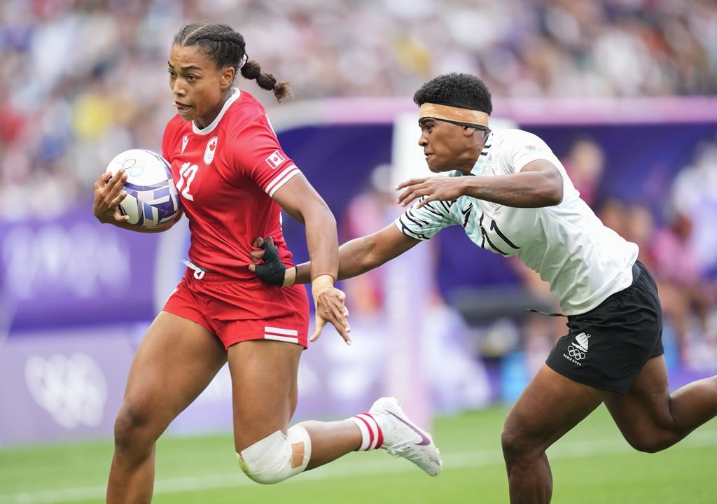 Canada back Keyara Wardley (12) scores a try past Fiji back Maria Rokotuisiga (11) during second half Women rugby 7s rugby action at the Paris Summer Olympics in Paris, France on Sunday, July 28, 2024. THE CANADIAN PRESS/Nathan Denette.