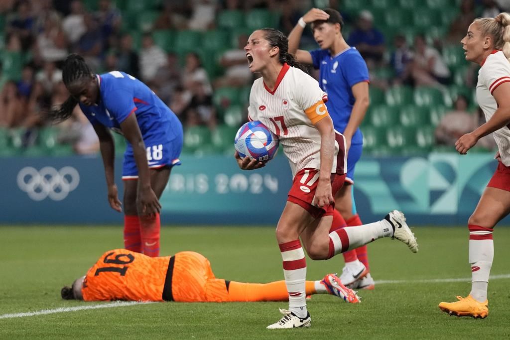 Canada's Jessie Fleming holds the ball as she celebrates after scoring her side's opening goal during the women's Group A soccer match between Canada and France at Geoffroy-Guichard stadium during the 2024 Summer Olympics, Sunday, July 28, 2024, in Saint-Etienne, France. THE CANADIAN PRESS/AP-Silvia Izquierdo.